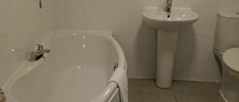 Un baño con bañera, lavabo e inodoro.