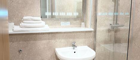 A modern bathroom with a toilet, sink, and glass-enclosed shower.