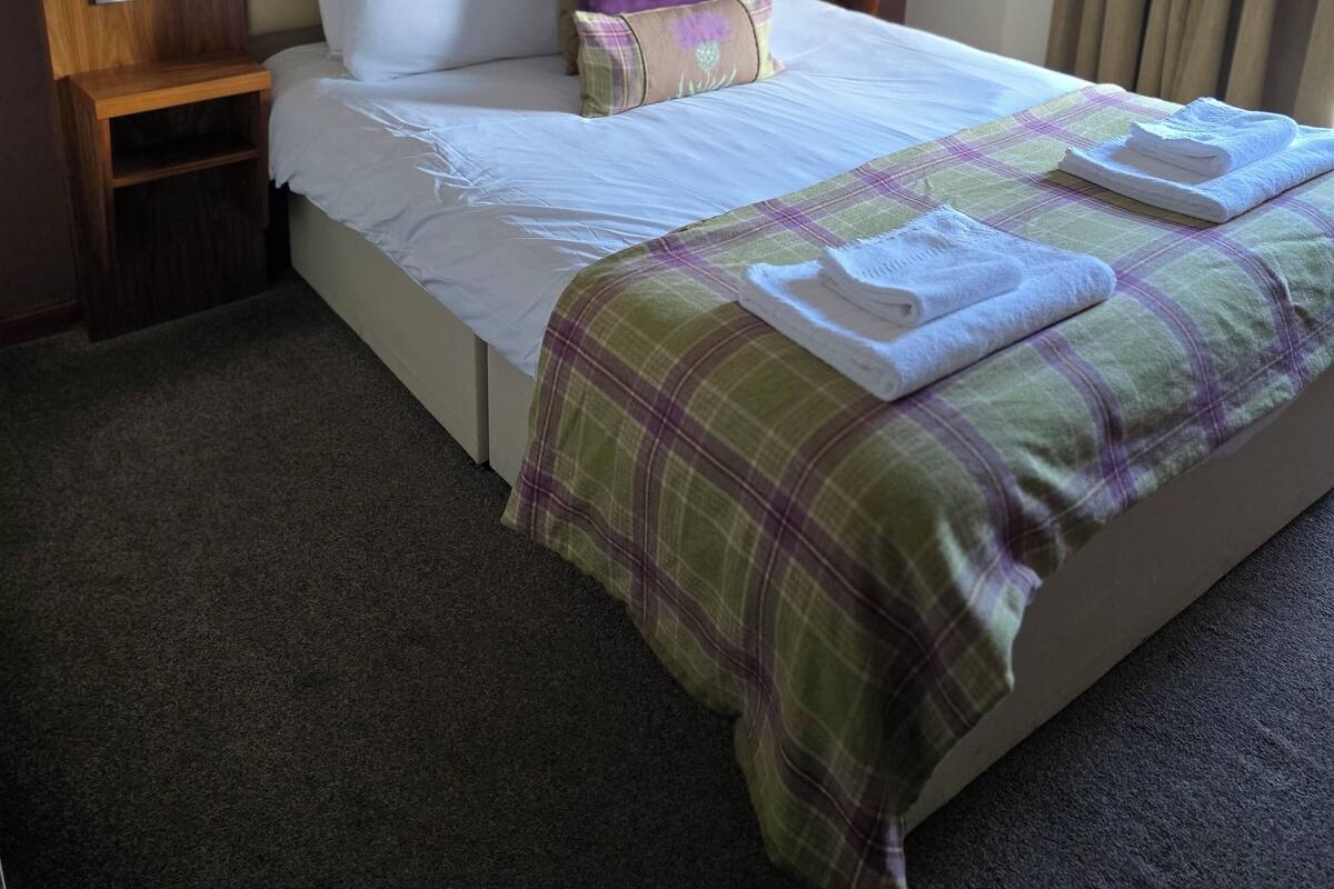 Ein Hotelzimmer mit einem großen Bett, einem Holzkopfteil und einer Karo-Bettdecke.