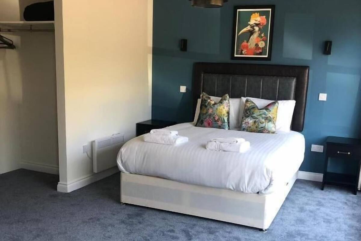 Ein Schlafzimmer mit einem großen Bett, einem dunklen Kopfteil und einem Bild an der Wand.