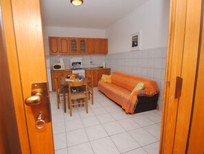Una cocina funcional con armarios de madera, una mesa de comedor con sillas y un sofá.