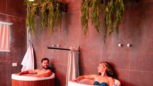 Un área de spa con dos tinas de madera, un perchero para toallas y una planta.