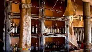 Una zona de bar rústica con estantes de madera y botellas.