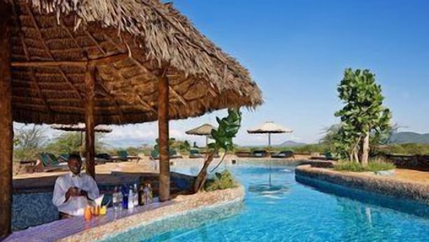 Una piscina con una estructura de techo de paja, una zona de bar y vistas del paisaje.