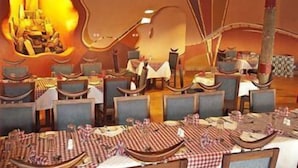 Un restaurante con una decoración única en forma de elefante, varias mesas de comedor con manteles a cuadros y una variedad de sillas.