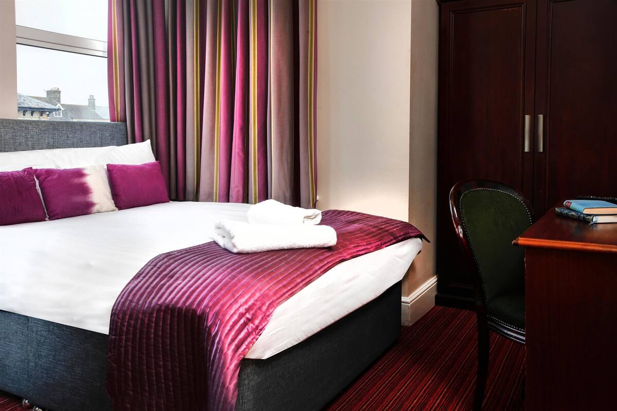 Ein Hotelzimmer mit einem großen Bett, einem Schreibtisch und einem Stuhl.