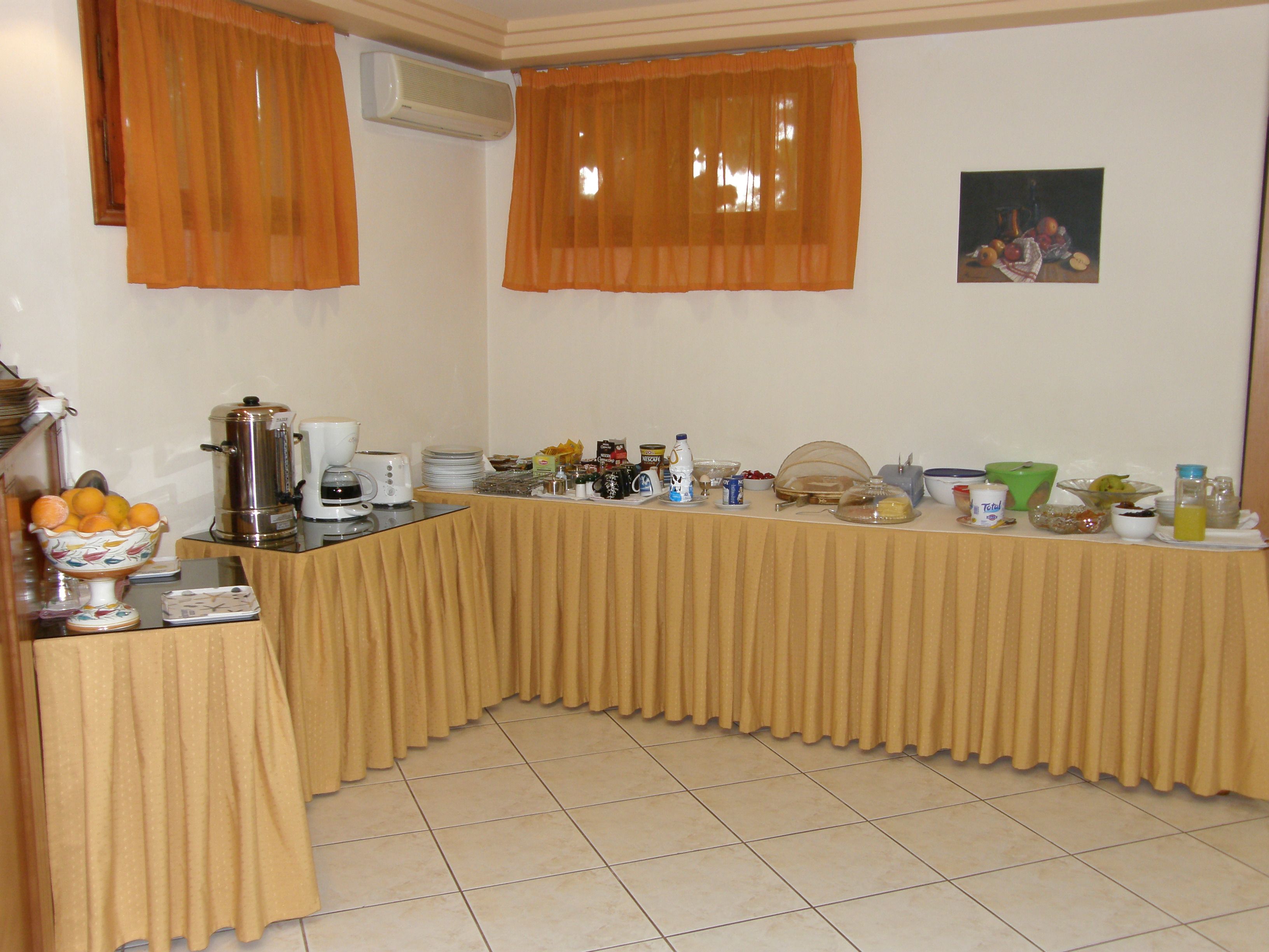A buffet setup with a variety of food items and beverages, a coffee maker, and a fruit bowl.