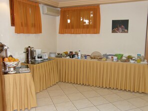 A buffet setup with a variety of food items and beverages, a coffee maker, and a fruit bowl. - Megim Hotel (Kantanos-Selino)