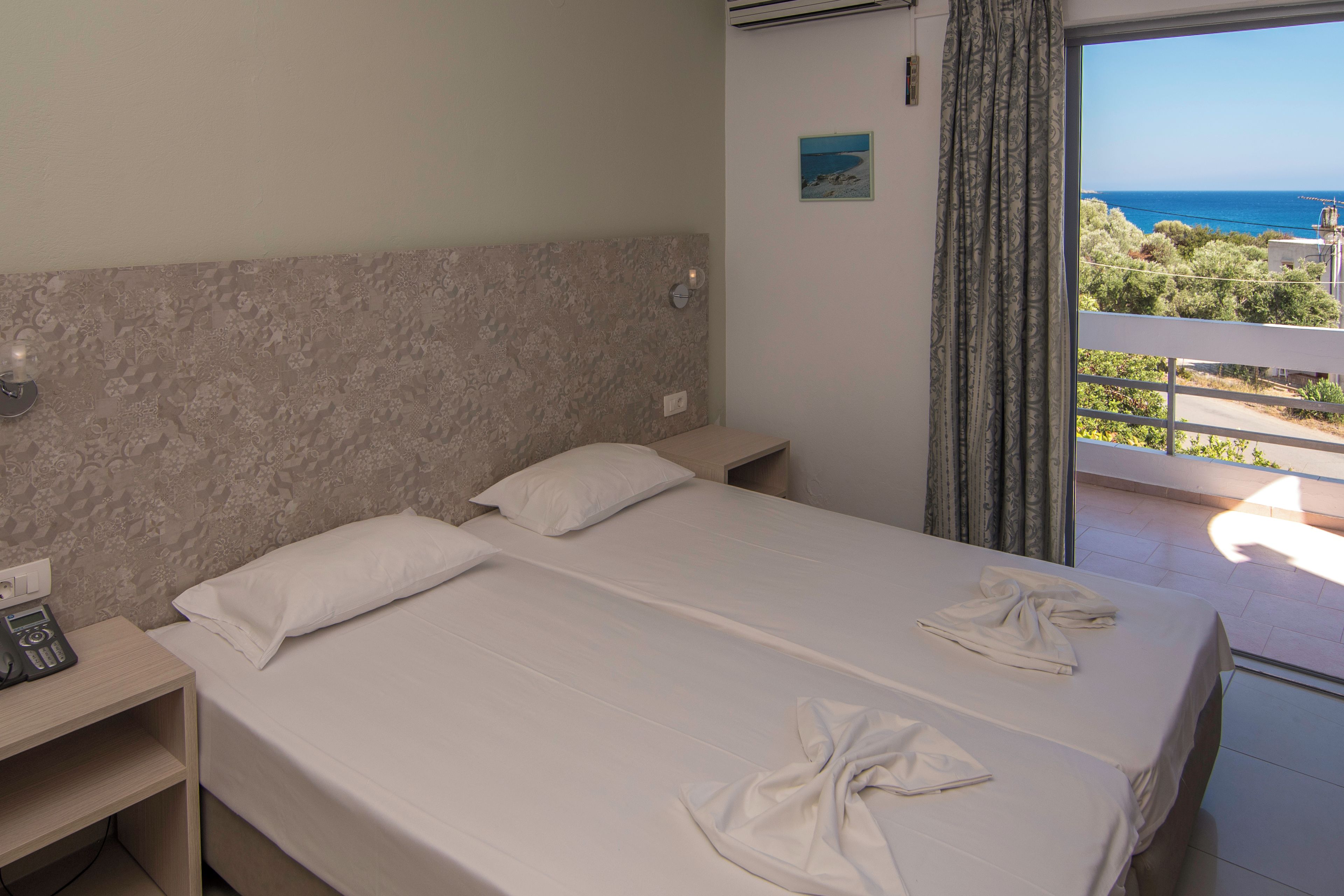 Ein Hotelzimmer mit Bett, Nachttisch, Telefon und Meerblick.