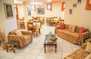 A spacious living room with a sofa, chairs, a coffee table, and a dining area with multiple tables and chairs. - Megim (Kantanos-Selino)