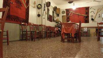 A dining area with wooden chairs and tables, a red carpet, and wall-mounted artifacts.