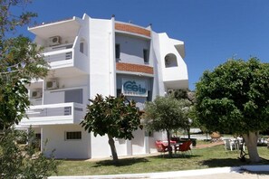 A multi-story hotel with a white facade, a visible logo, and outdoor seating. - Megim Hotel (Kantanos-Selino)