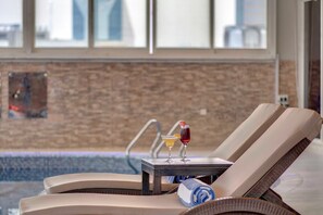 A sun lounger with a towel and a drink by a poolside. - Lotus Grand Hotel Dubai (Dubai)