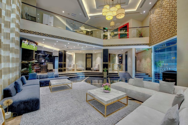 A spacious lobby with a high ceiling, modern furniture, and a large flat-screen TV.