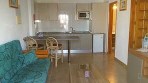 Una cocina compacta con comedor, sofá y refrigerador.