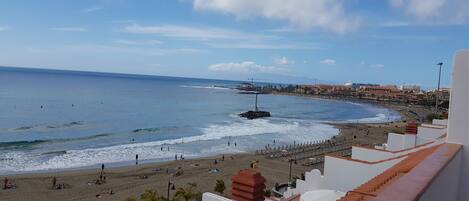 A coastal view with a beach, ocean, and buildings in the background.