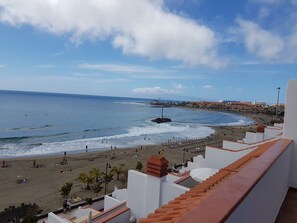 Vista costera con playa, océano y edificios al fondo.