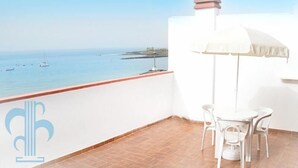 A balcony with a view of the sea, a table with chairs, and two blue cushioned chairs. - Las Fuentes (Arona)