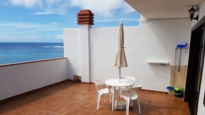 A balcony with a table and chairs, a view of the ocean, and a tiled floor. - Las Fuentes (Arona)