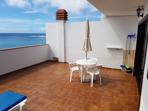 A balcony with a table and chairs, a view of the ocean, and a tiled floor. - Las Fuentes (Arona)