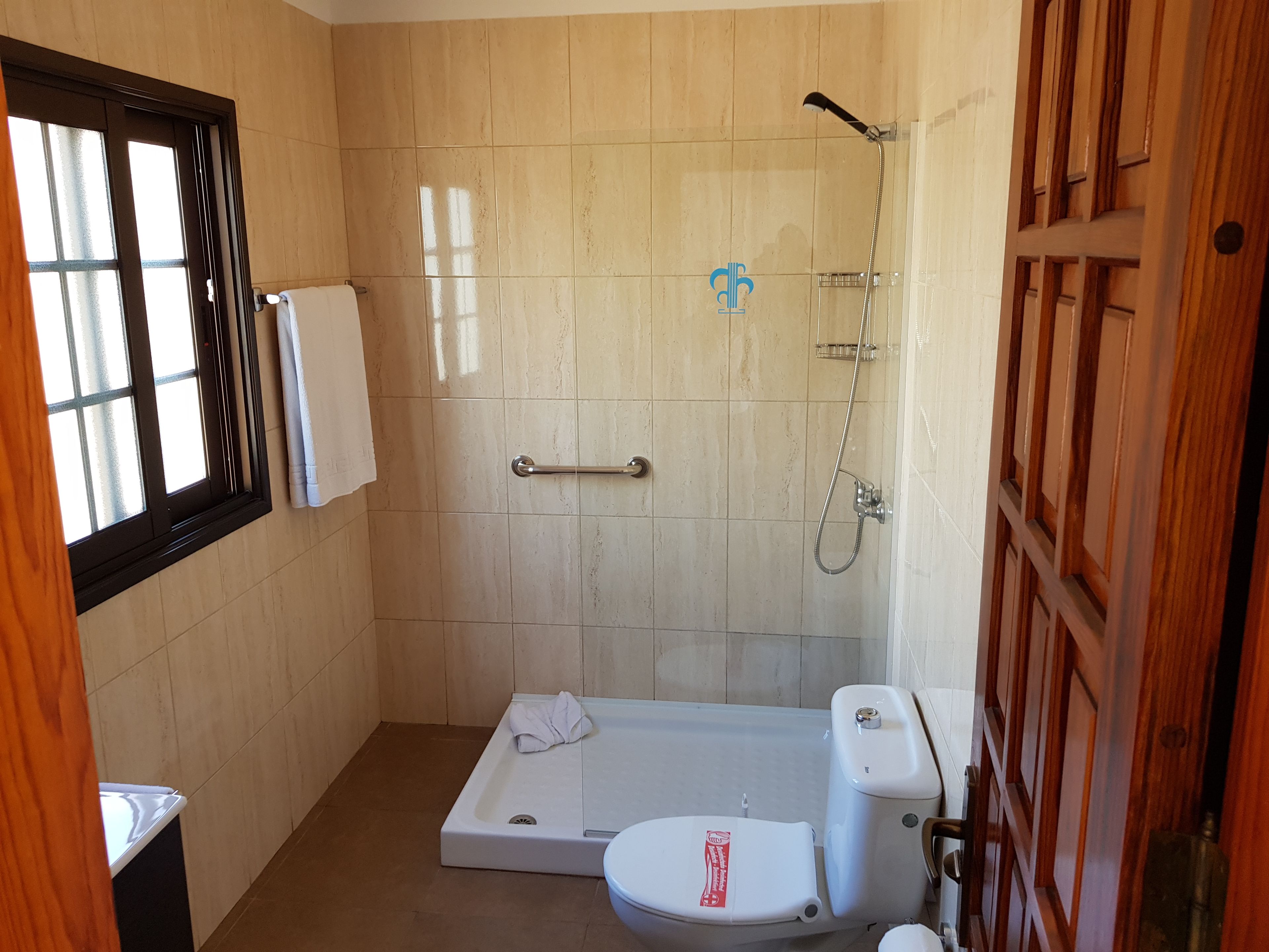 Un baño con ducha, inodoro y ventana.