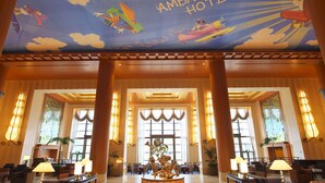 A lobby with a Disney Ambassador Hotel sign, large windows, and a central statue. - Disney Ambassador Hotel (Urayasu)