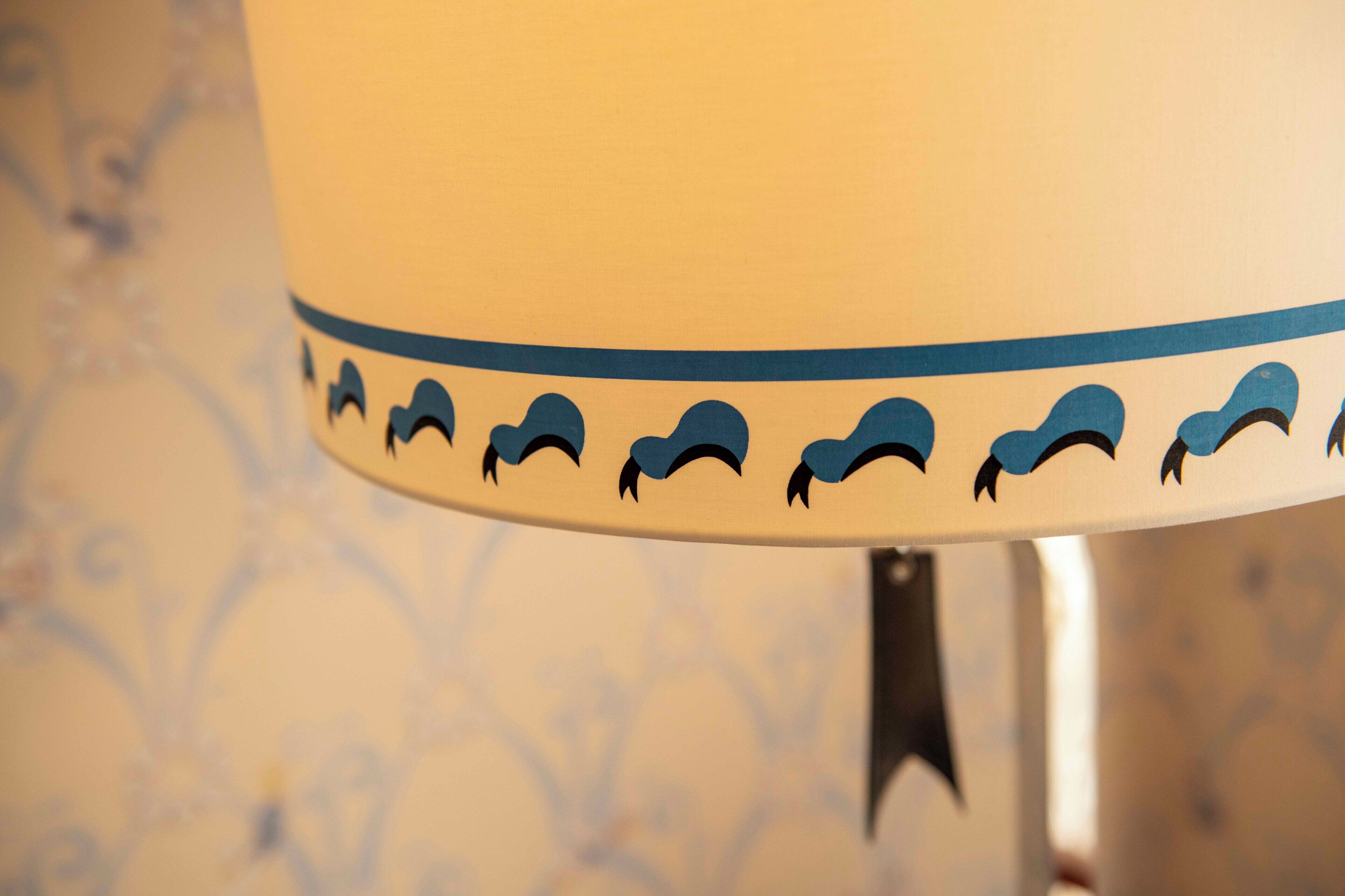 A lamp with a blue border and a pattern of birds.