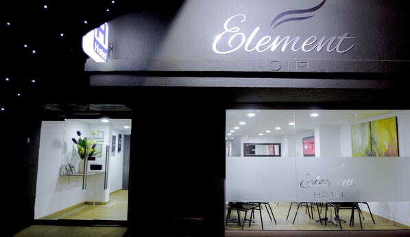 The entrance of Element Hotel with a reception desk, a glass partition, and a seating area with chairs.