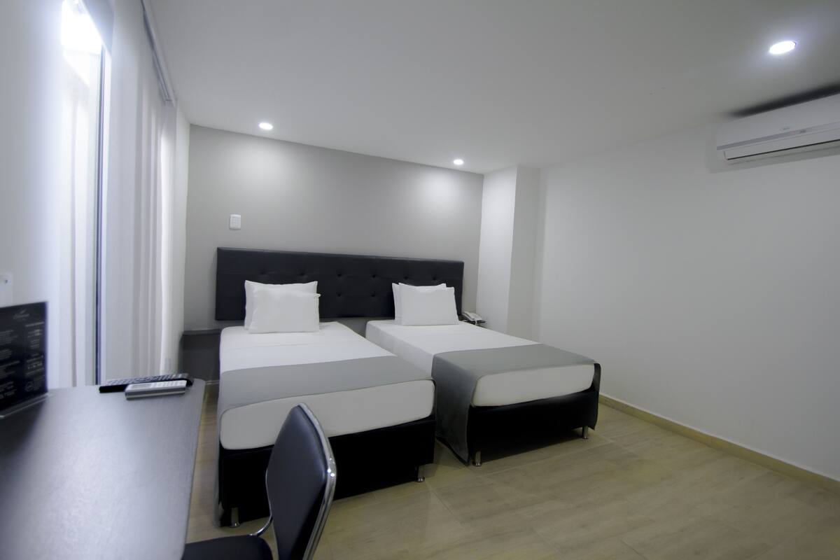 Habitación de hotel con dos camas, un escritorio y una silla.