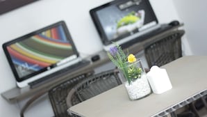 A laptop on a table with a glass vase containing flowers and a candle.