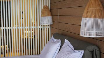 Una cama con ropa de cama blanca, un cabecero gris y dos lámparas blancas con pantallas de madera.
