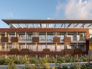 A modern multi-story building with balconies, large windows, and wooden paneling. - Ikones Seafront Luxury Suites (Rethymno)