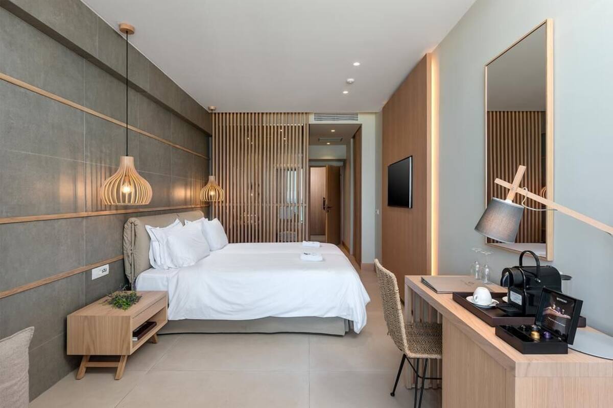 Een moderne hotelkamer met een bed, nachtkastje en bureau met stoel.
