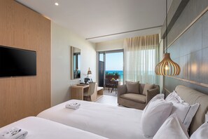 Habitación de hotel con una cama grande, un escritorio, una silla, un sofá, un televisor y un balcón con vistas.
