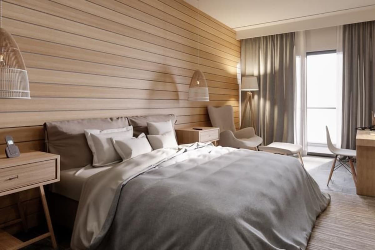 A modern hotel room with a large bed, bedside tables, a desk, and a chair.