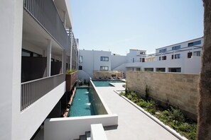 A modern building with a swimming pool and outdoor seating areas. - Ikones Seafront Luxury Suites (Rethymno)