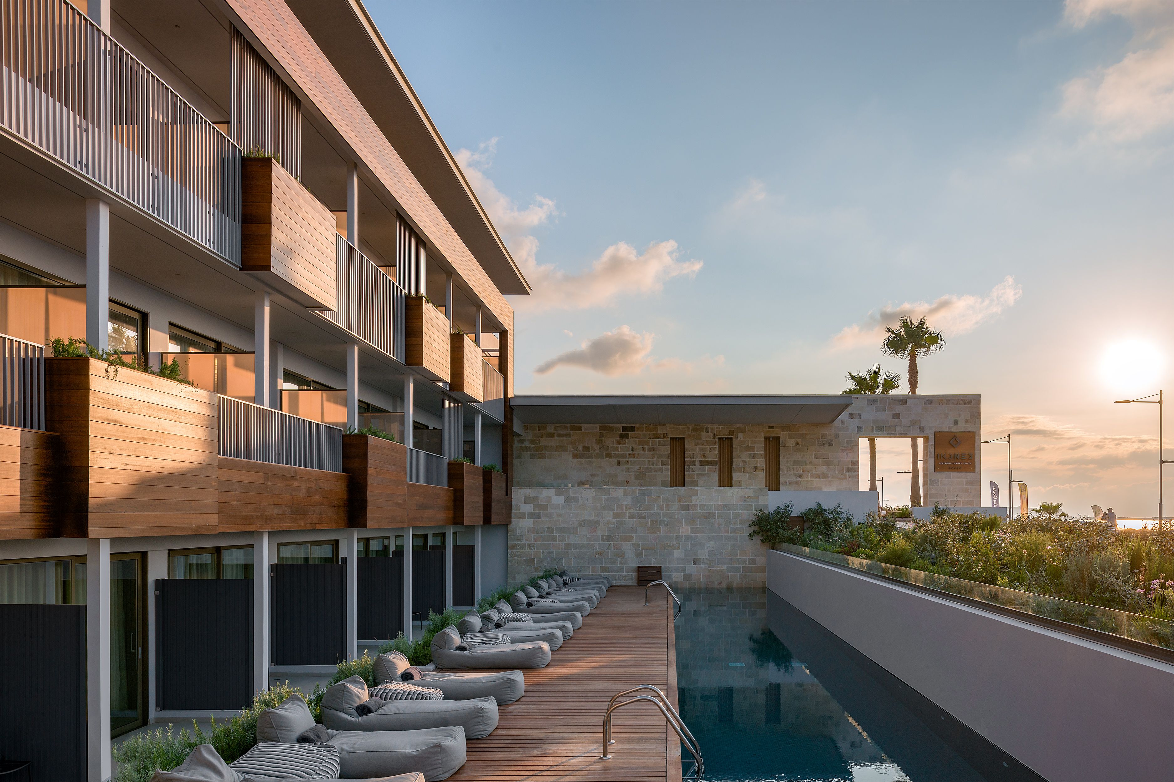 Un hotel moderno con piscina, terraza de madera y balcones.