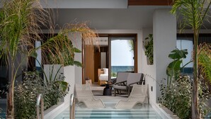 A pool area with lounge chairs, a wooden deck, and a view of the ocean. - Ikones Seafront Luxury Suites (Rethymno)