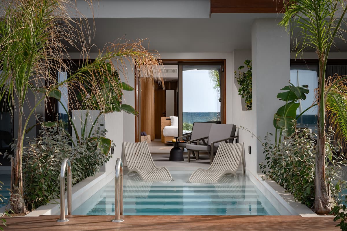 A pool area with lounge chairs, a wooden deck, and a view of the ocean.