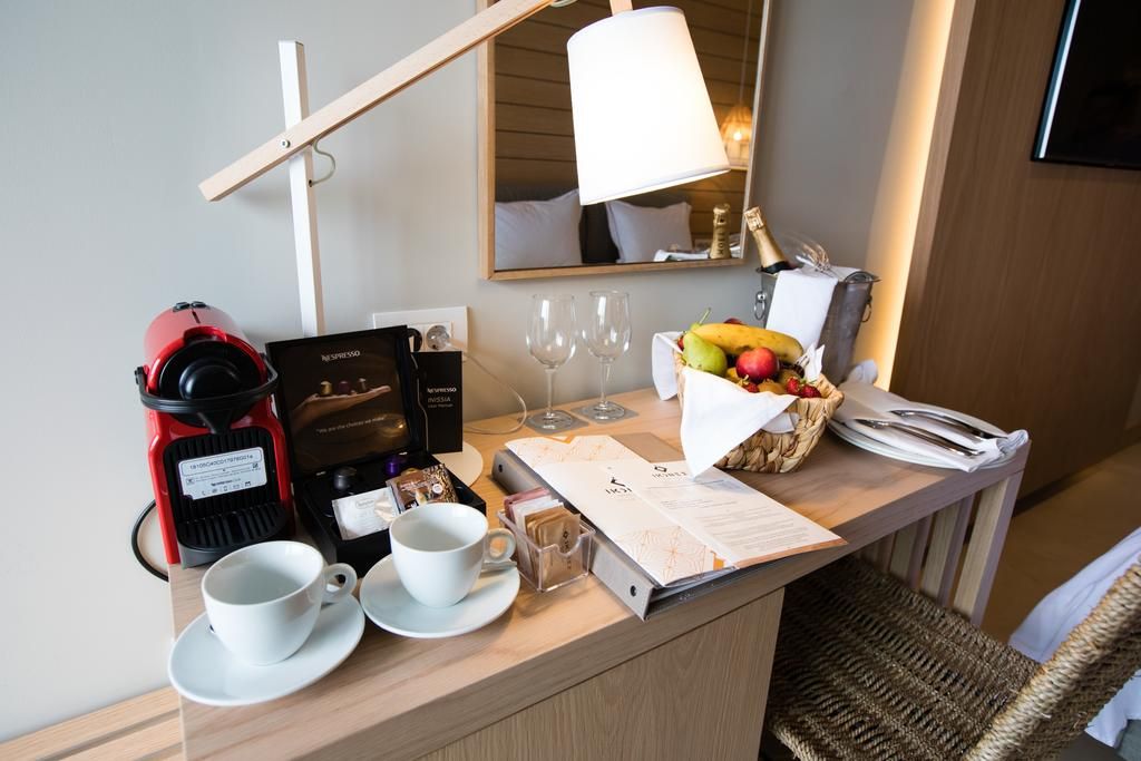 Zona de petit esmorzar d'una habitació d'hotel, amb una cafetera, una cistella de fruita, un menú i una làmpada.