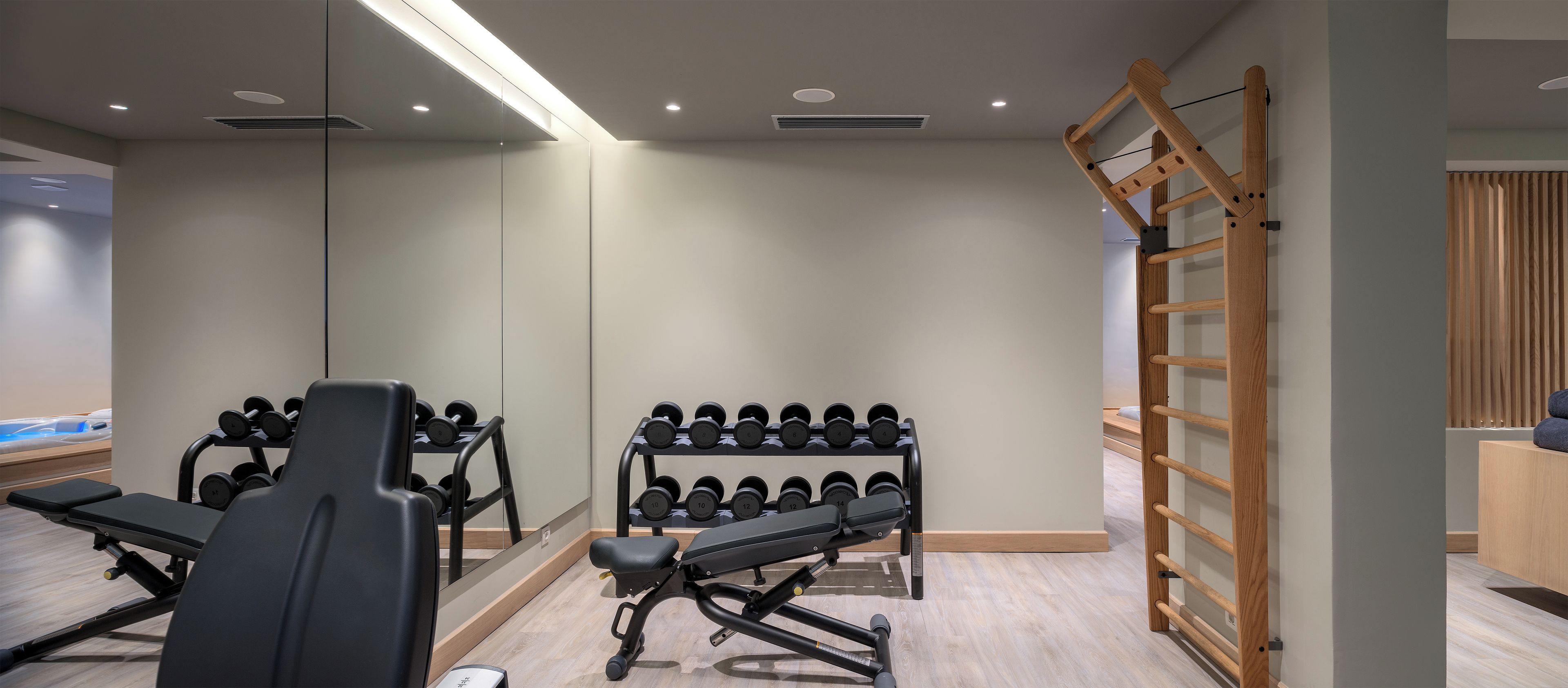 Un gimnasio con equipo de ejercicio, incluyendo bancos y mancuernas, además de una escalera de madera.