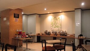A modern restaurant with a wooden counter, seating area, and a wall-mounted plant. - Alma Hotel (Jakarta)