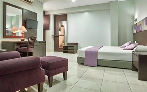 A hotel room with a bed, a desk, a chair, and a television. - Alma Hotel (Jakarta)