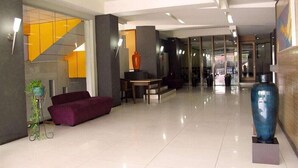 A modern lobby with a purple sofa, a dining table, and a large blue vase. - Alma Hotel (Jakarta)