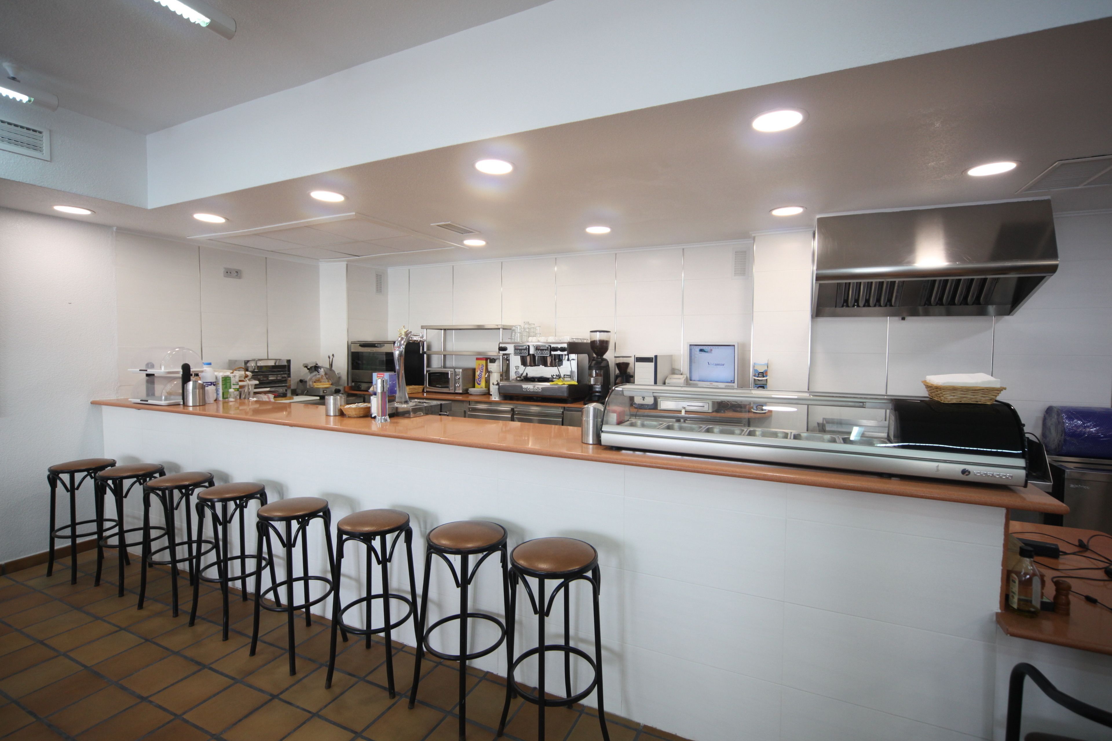 Una cocina moderna con una encimera larga, taburetes de bar y diversos electrodomésticos.