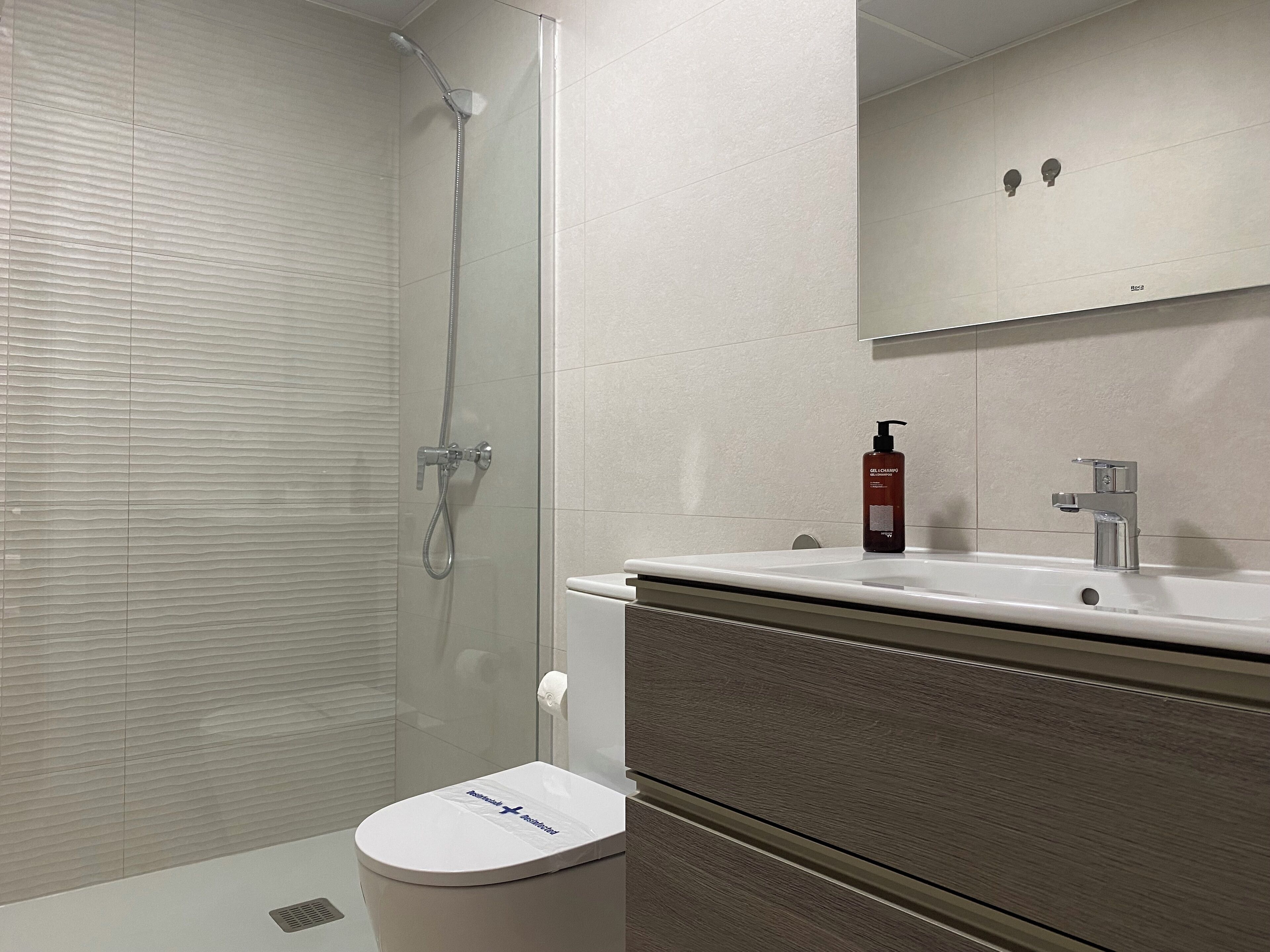 A modern bathroom with a shower, toilet, and sink.