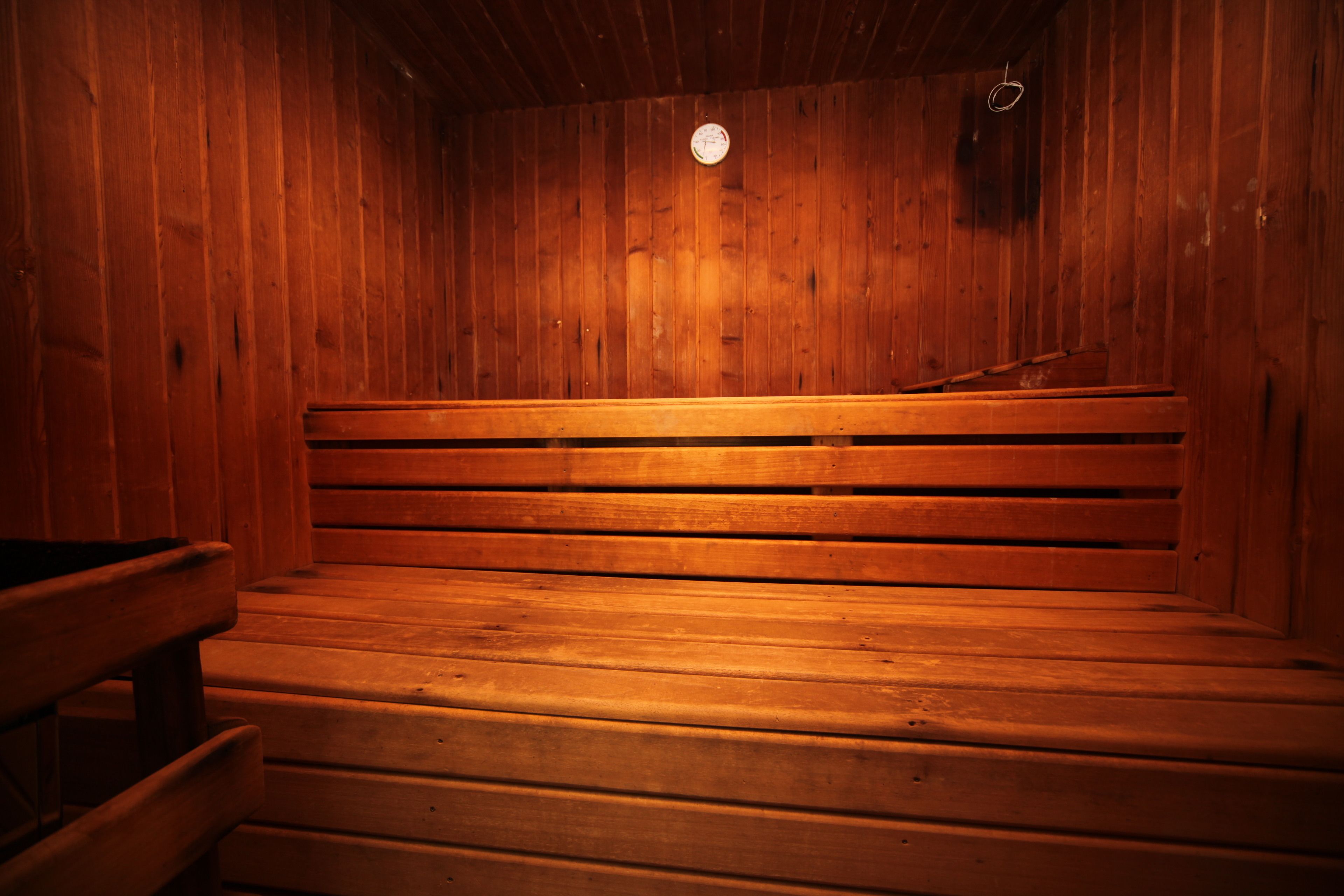 Una sauna con bancos de madera e iluminación circular en el techo.