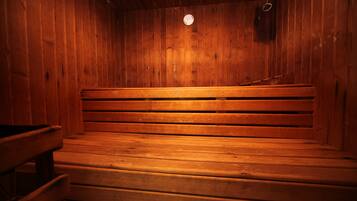 Una sauna con bancos de madera e iluminación circular en el techo.