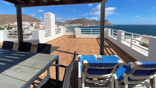 A terrace with a view of the sea, a table, and chairs. - Aparthotel Vistamar (Nijar)