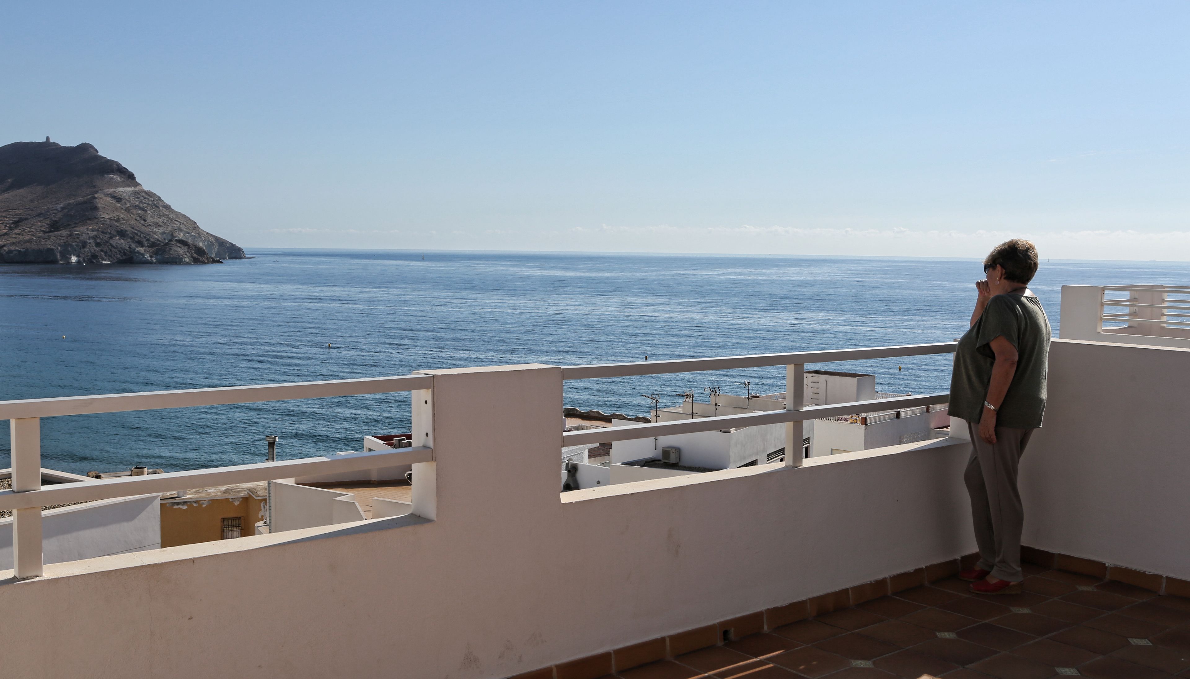 A balcony with a view of the sea and a rocky island.